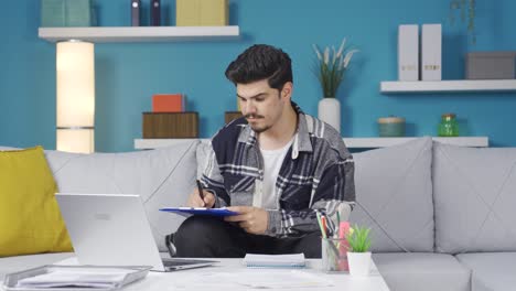 Home-office-worker-taking-notes-while-looking-at-computer.